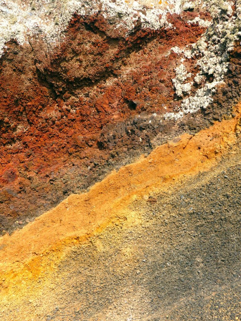 Detailed view of vibrant volcanic rock layers on Santorini, Greece, showcasing natural geological patterns.